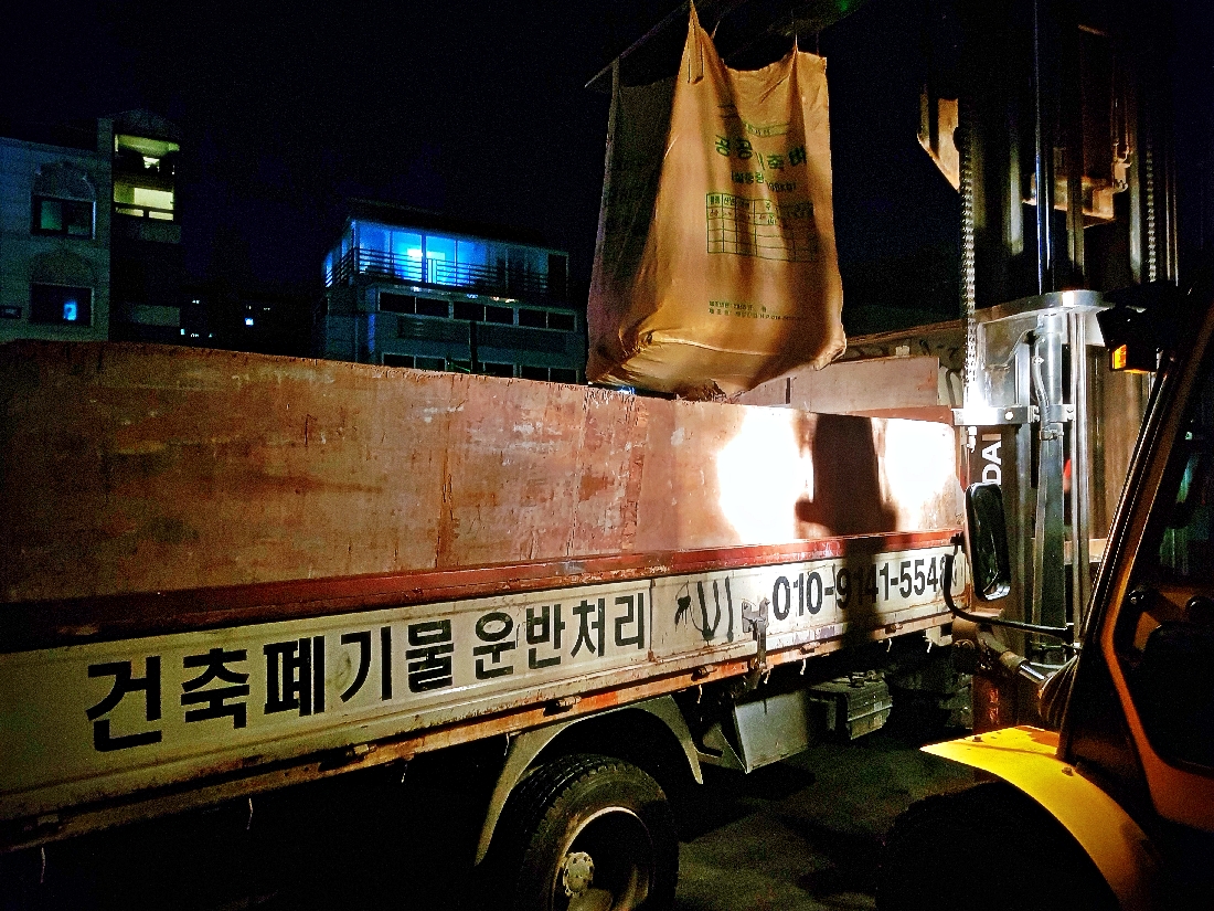 야간 강서구 현장에서 지게차가 항공마대 폐콘크리트를 2.5톤 차량에 상차하는 모습