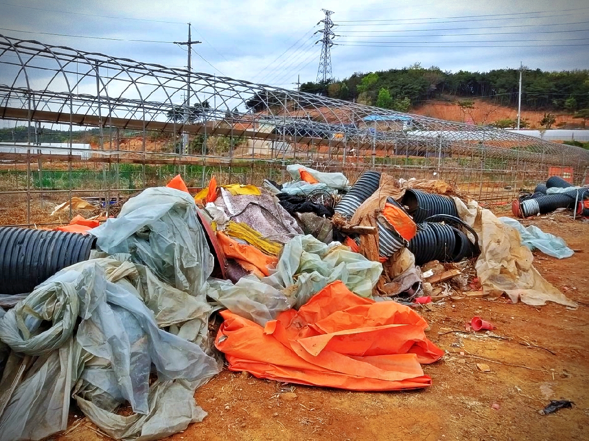 비닐류와 선형 관재, 흰 보온재로 보이는 조각이 섞여 놓인 실제 사진